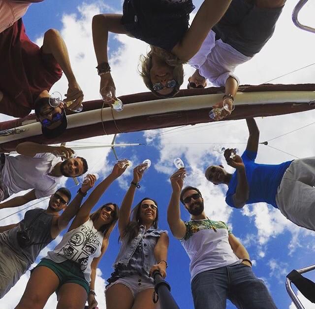 Friends raising their glasses during a sailboat party, seen from below