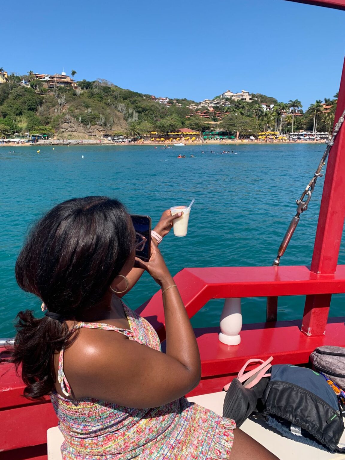 Traveler photographing the turquoise water of Búzios from a boat tour