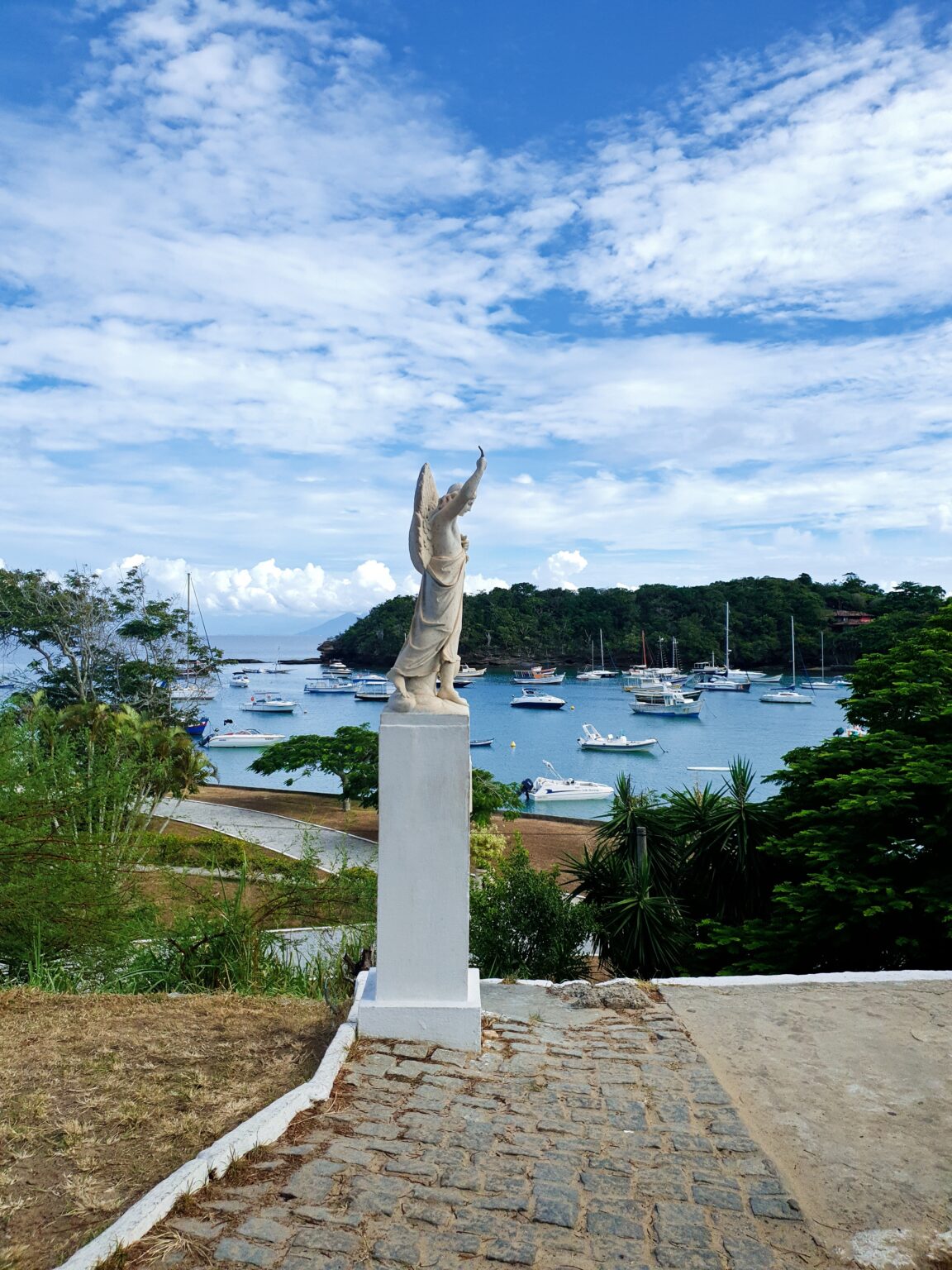 Statue at the Praia dos Ossos lookout overlooking boats in Búzios bay