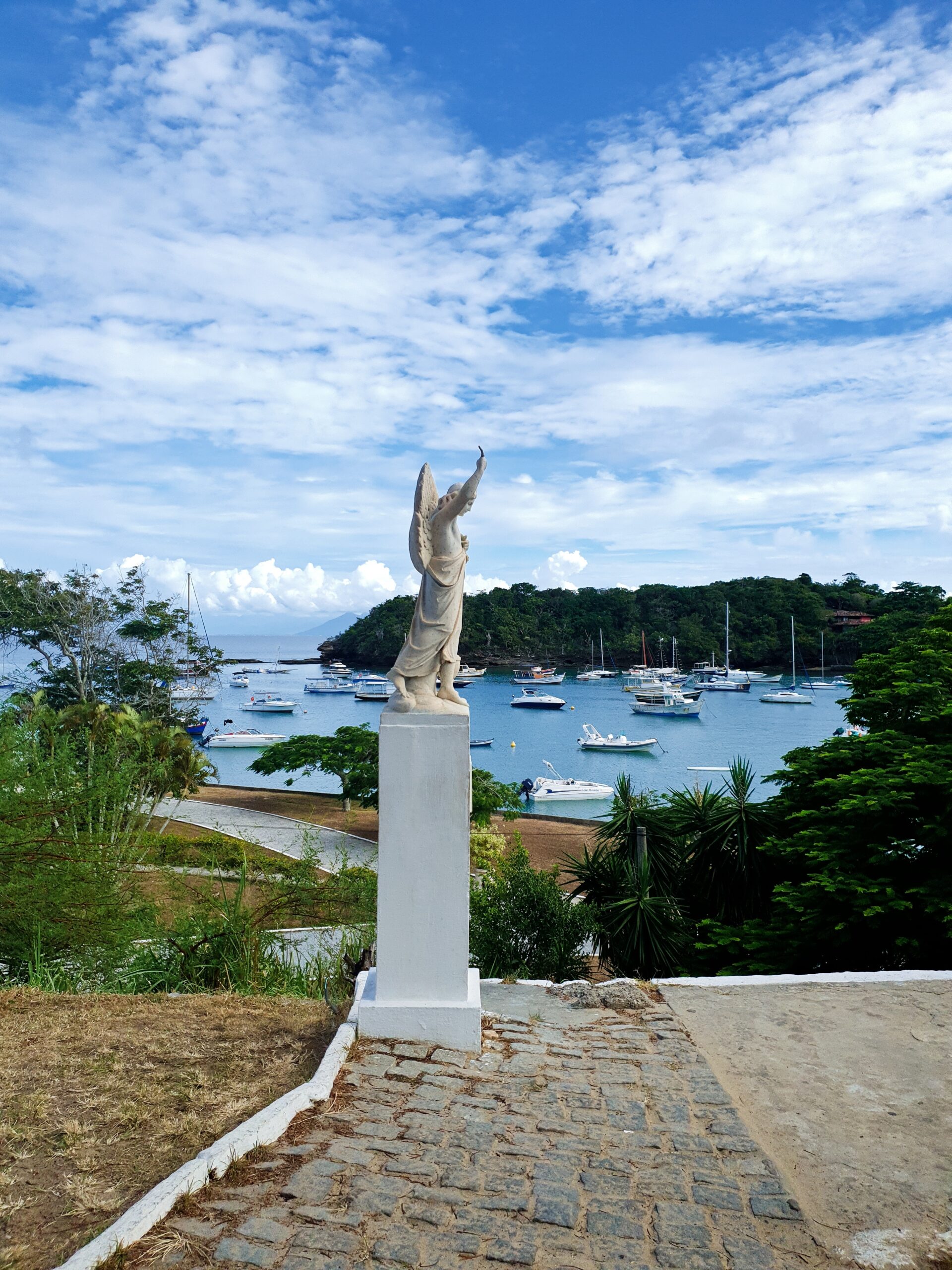 Statue at the Praia dos Ossos lookout overlooking boats in Búzios bay