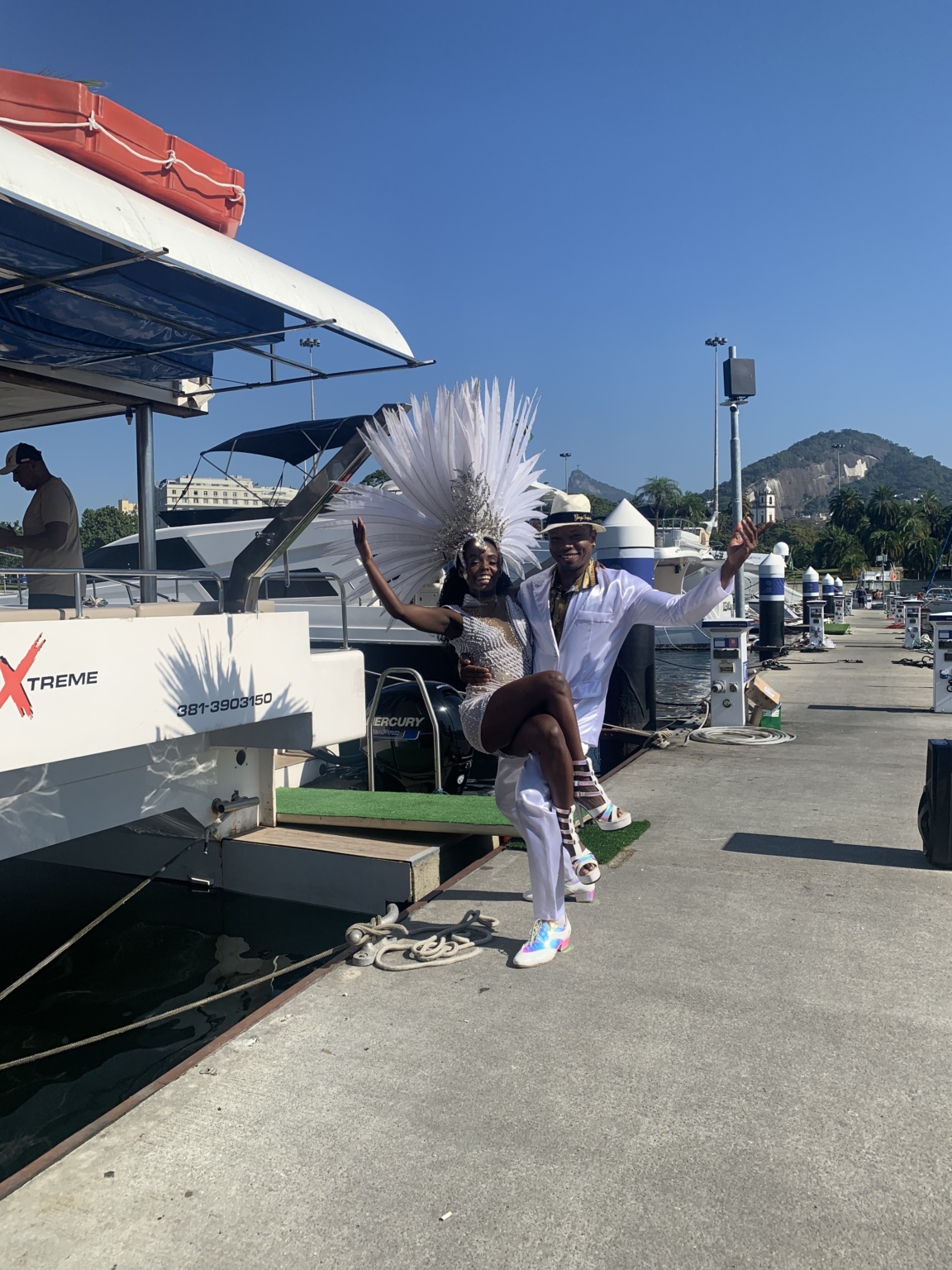 Samba dancer in a feathered costume welcoming guests at the catamaran pier