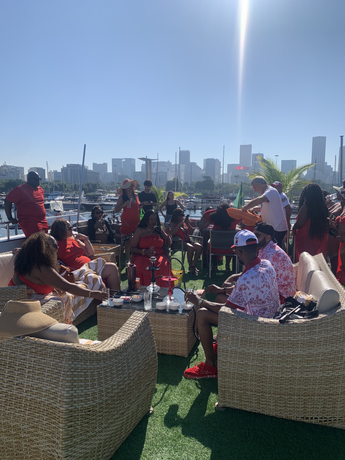 Guests relaxing on the deck lounge of a private catamaran with the Rio skyline behind