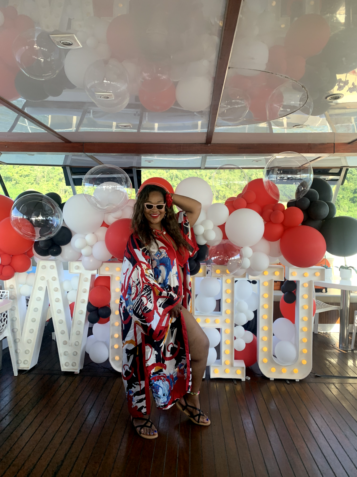 Guest posing with red and white balloon decorations at a private catamaran party