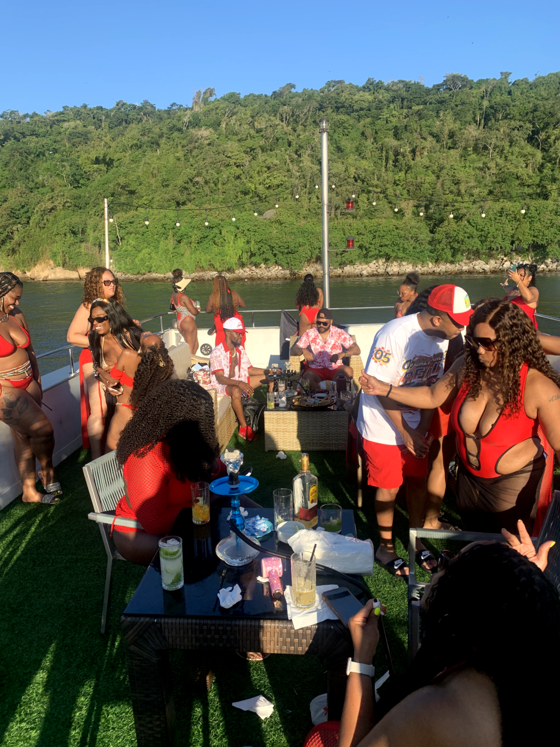 Group of guests in red and white outfits enjoying a private catamaran party in Rio de Janeiro