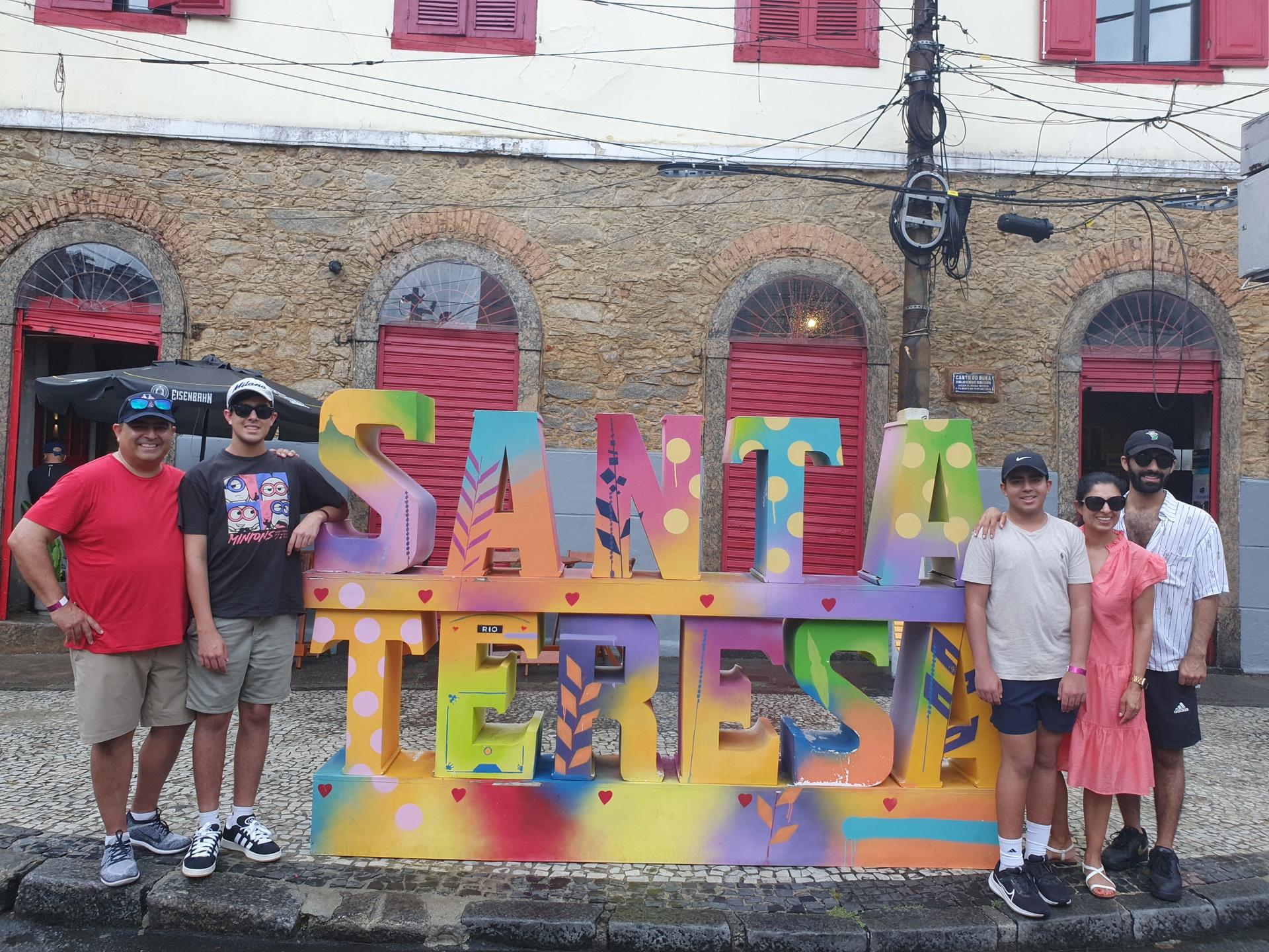 Travelers posing with the colorful Santa Teresa sign in Rio de Janeiro