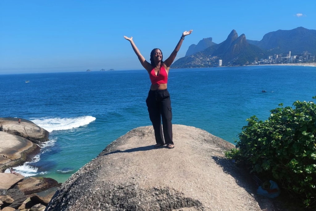 Traveler celebrating on Pedra do Arpoador with the ocean and Two Brothers Hill behind