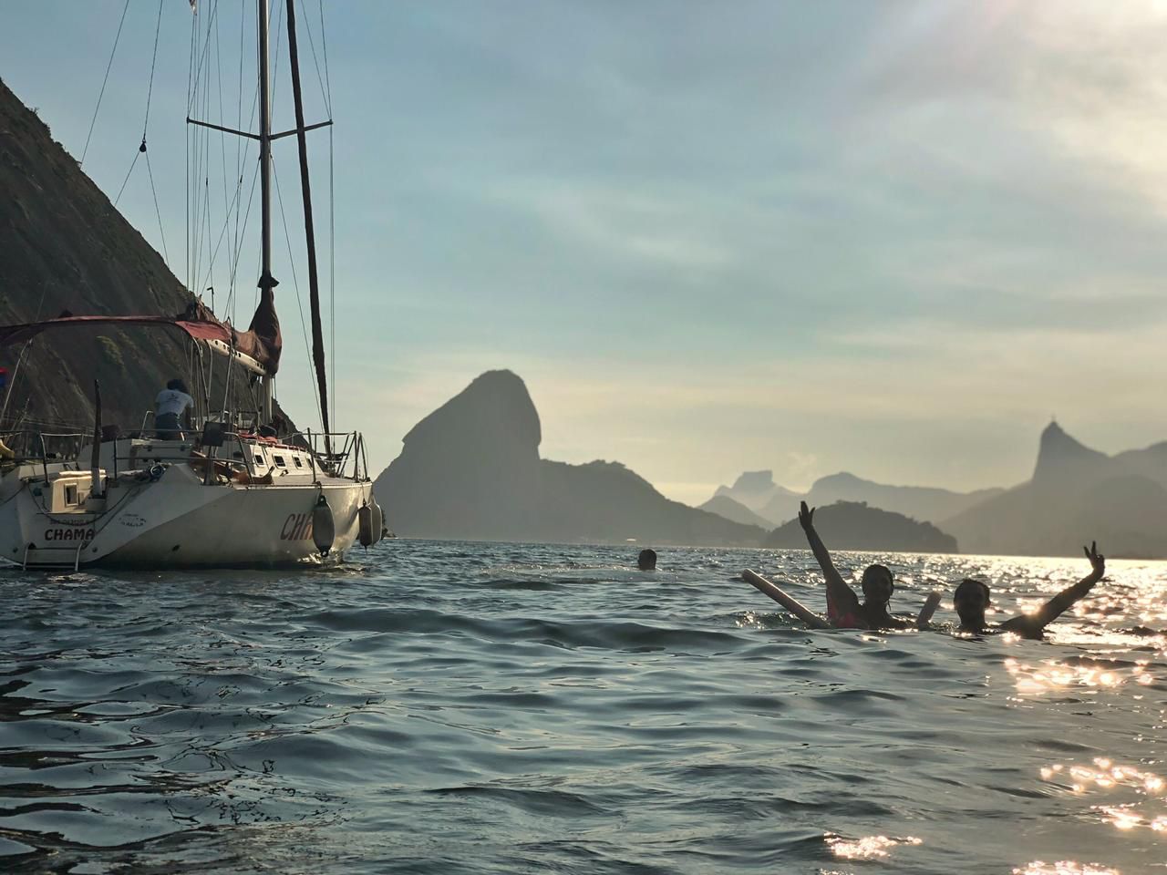 Guest swimming next to an anchored sailboat with Sugarloaf Mountain in the background